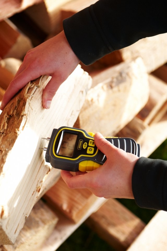 Moisture meter being used on the freshly split face of firewood